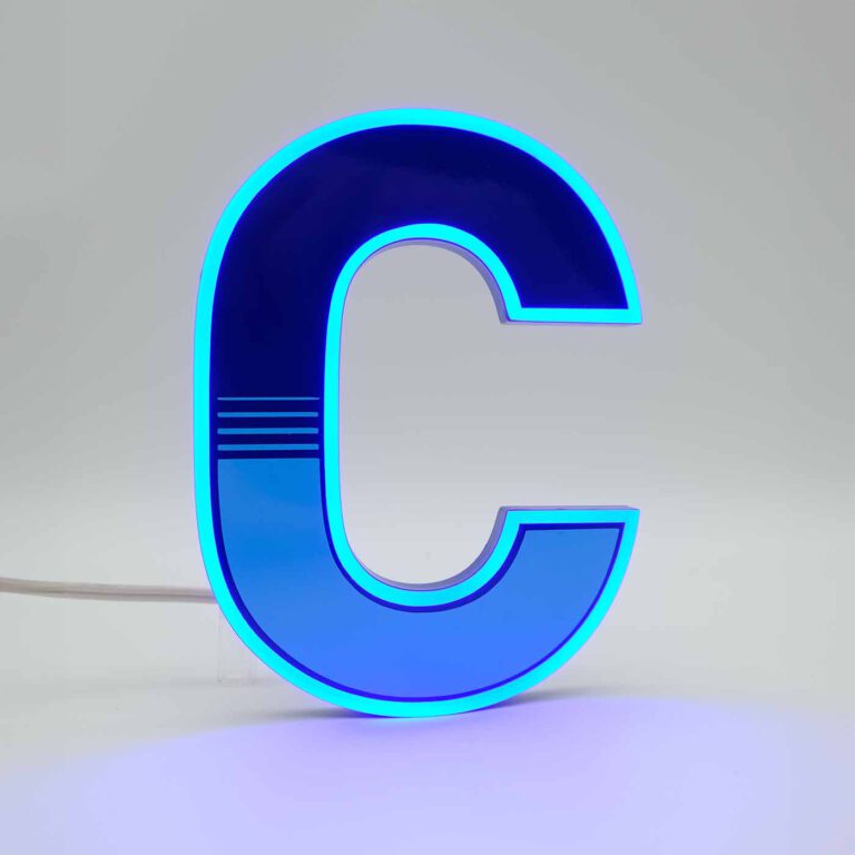 MaxxLuxx präsentiert einen aufrecht stehenden Neon-Konturleuchter in der Form des Buchstabens "C". Der leuchtende, blaue Buchstabe hebt sich vor einem weißen Hintergrund ab. Auf der Frontseite des Buchstabens befindet sich eine lichtundurchlässige blaue Folie mit einem sanften optischen Verlauf. Die Konturen des Buchstabens sind frei und strahlen in einem hellen, blauen Licht.